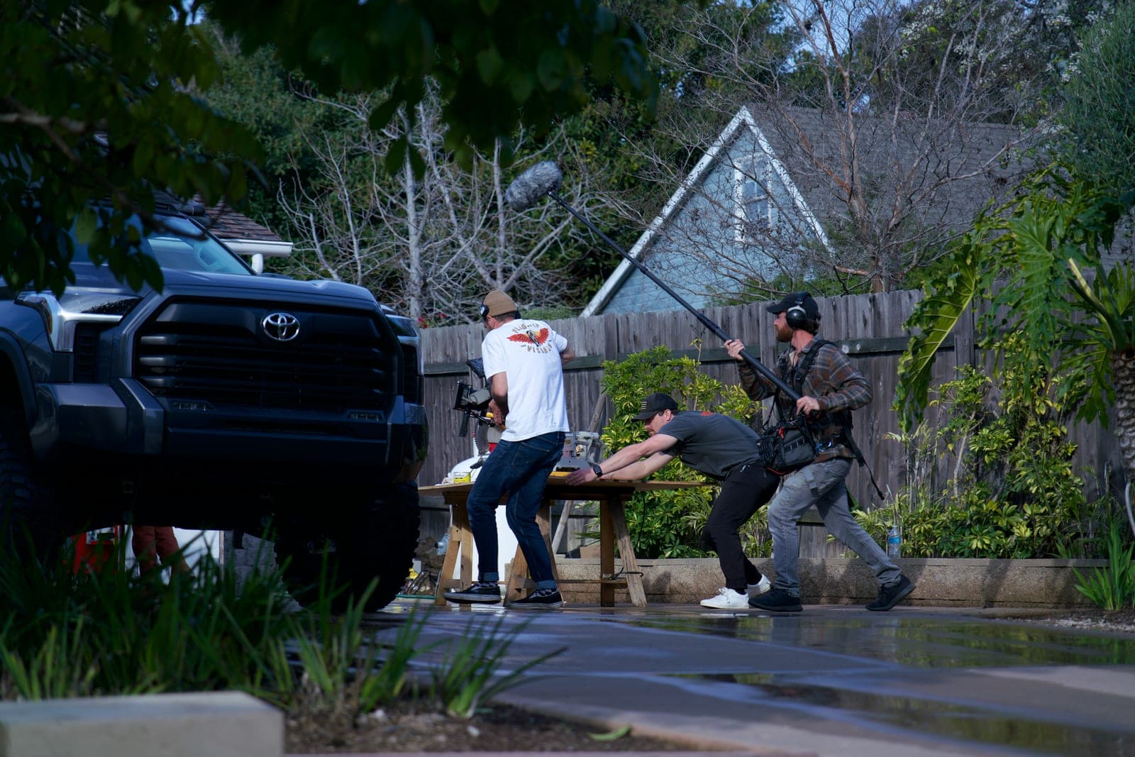 A backyard scene shot at dusk, boom operator swinging in over a table while the camera operator holds on talent